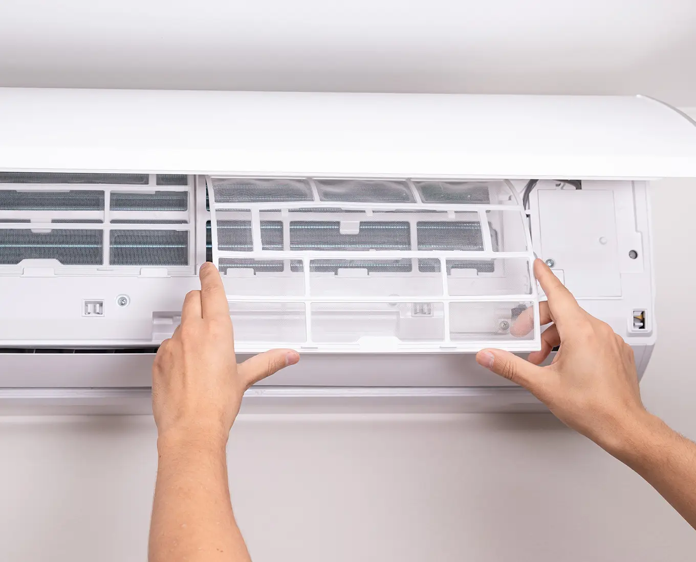 Hands removing and cleaning a mini split air conditioner filter during routine cooling system maintenance in Springfield, IL.