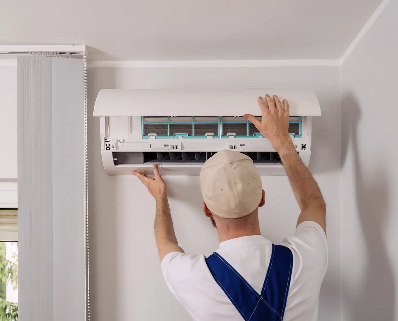 HVAC technician inspecting and servicing a wall-mounted mini split system during air conditioning maintenance in Springfield, IL.