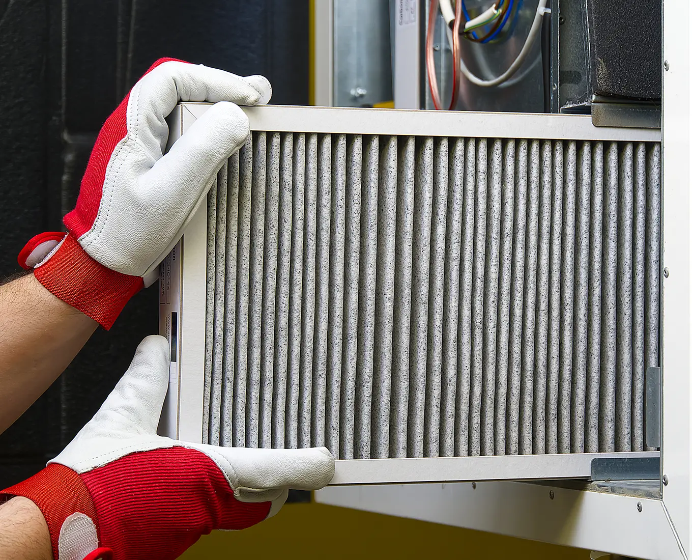 Technician replacing a residential HVAC air filter as part of routine AC maintenance service in Springfield, IL.