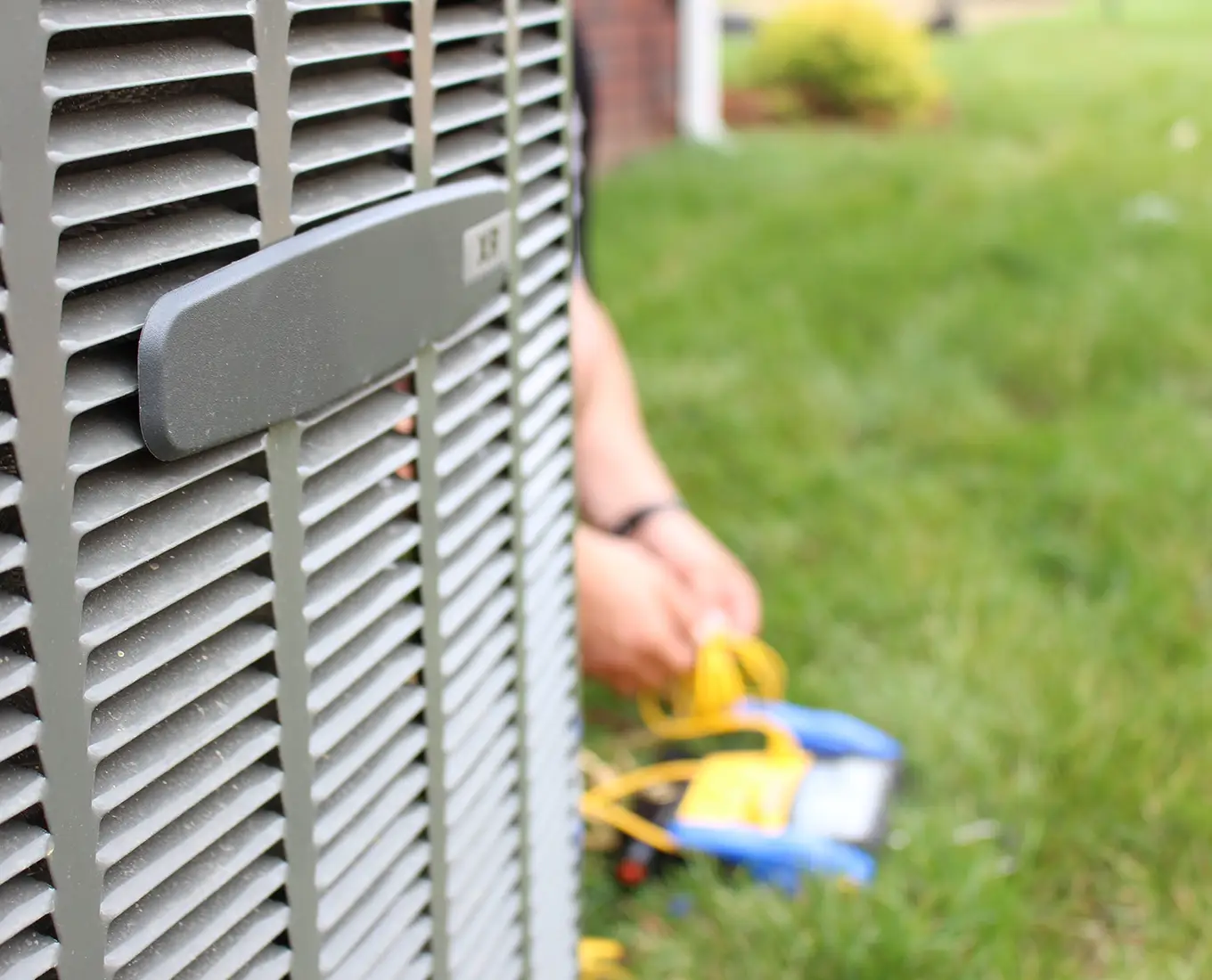 Technician performing diagnostics and air conditioning repair on an outdoor AC condenser unit in Springfield, IL.