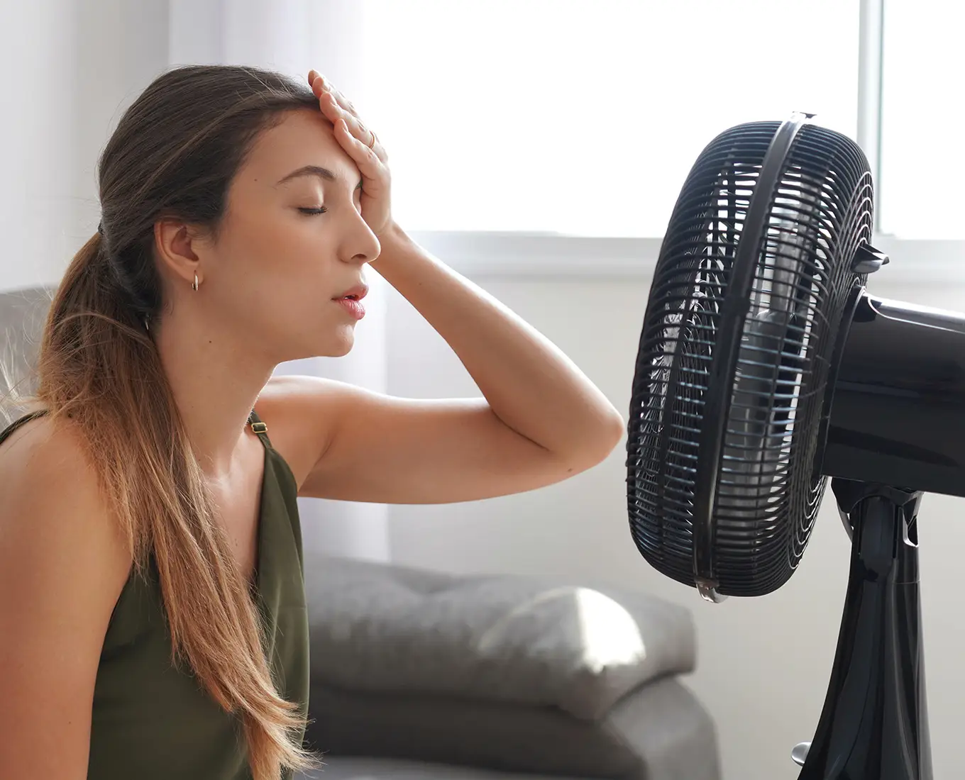 Homeowner feeling overheated indoors before scheduling professional AC repair services in Springfield, IL.