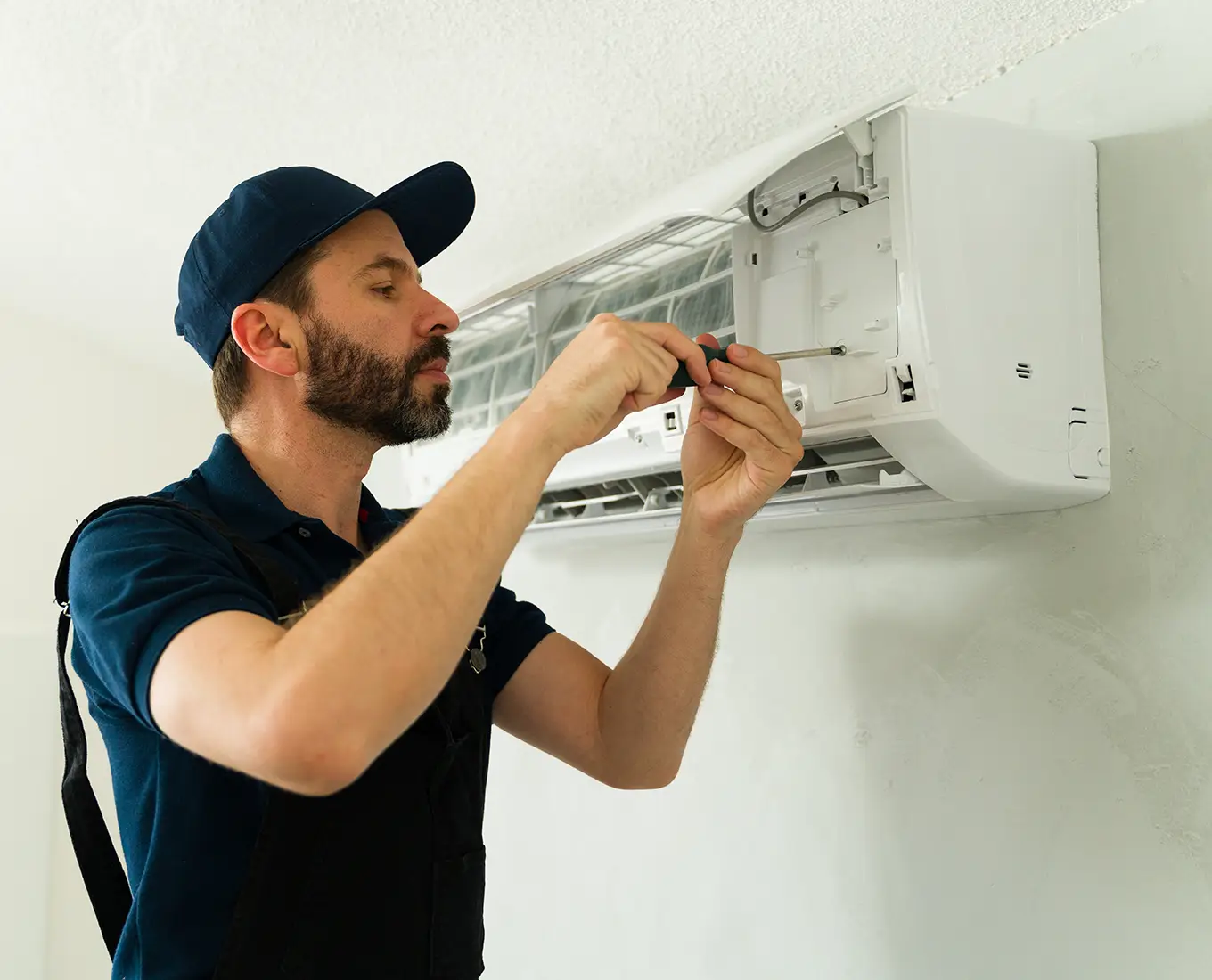 HVAC technician repairing a wall-mounted ductless mini split system during air conditioning repair service in Springfield, IL.