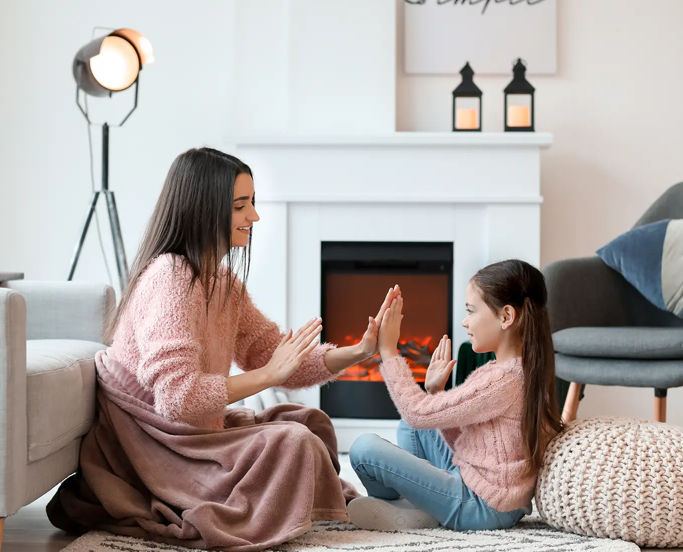 Mother and daughter enjoying a warm living room by the fireplace, representing reliable furnace maintenance services keeping homes comfortable in Springfield, IL.