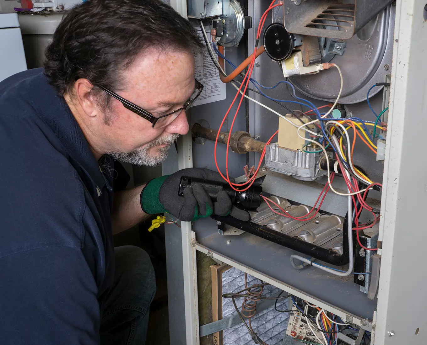 HVAC technician inspecting wiring and components inside a residential furnace during professional furnace maintenance service in Springfield, IL.