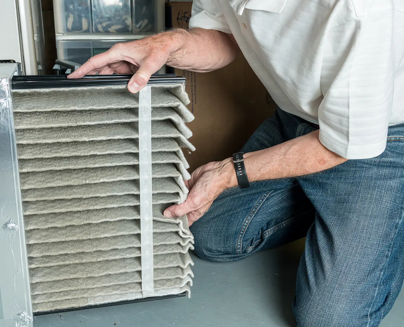 Homeowner replacing a dirty HVAC air filter as part of routine furnace maintenance to improve indoor air quality in Springfield, IL homes.