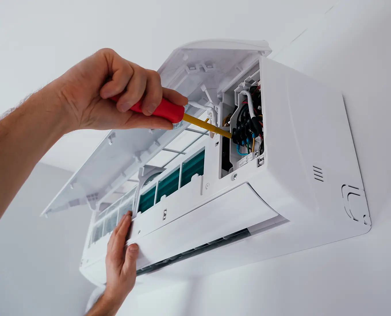 Technician repairing a wall-mounted ductless mini-split system during ductless HVAC repair service in Springfield, IL.