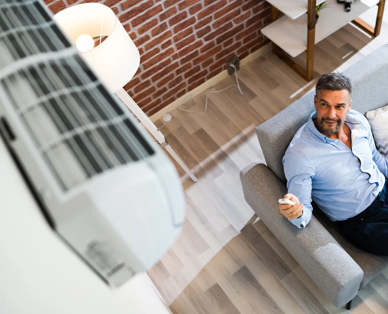 Homeowner adjusting a ductless mini-split air conditioner with a remote control for efficient heating and cooling in Springfield, IL.